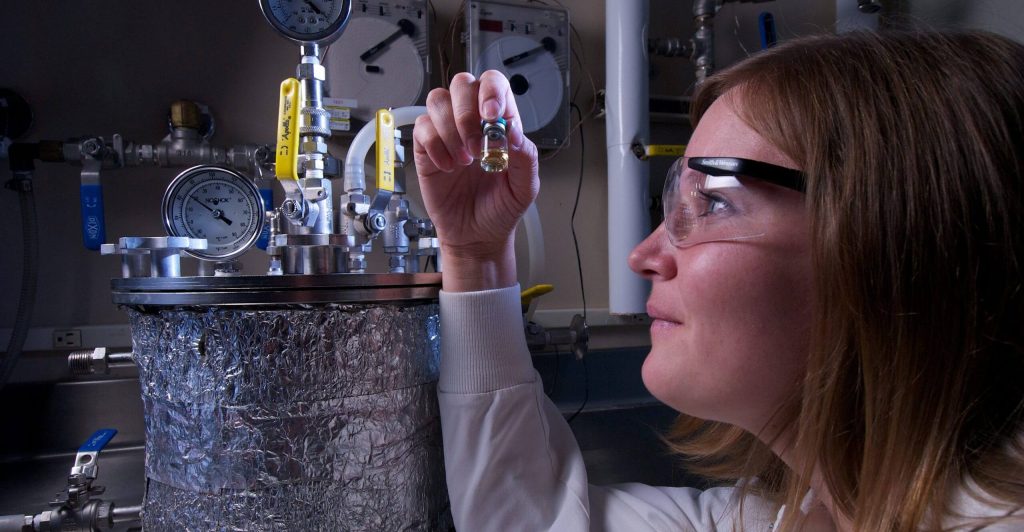 Nelson Labs employee alongside a pressure vacuum used for immersion testing such as bacterial immersion